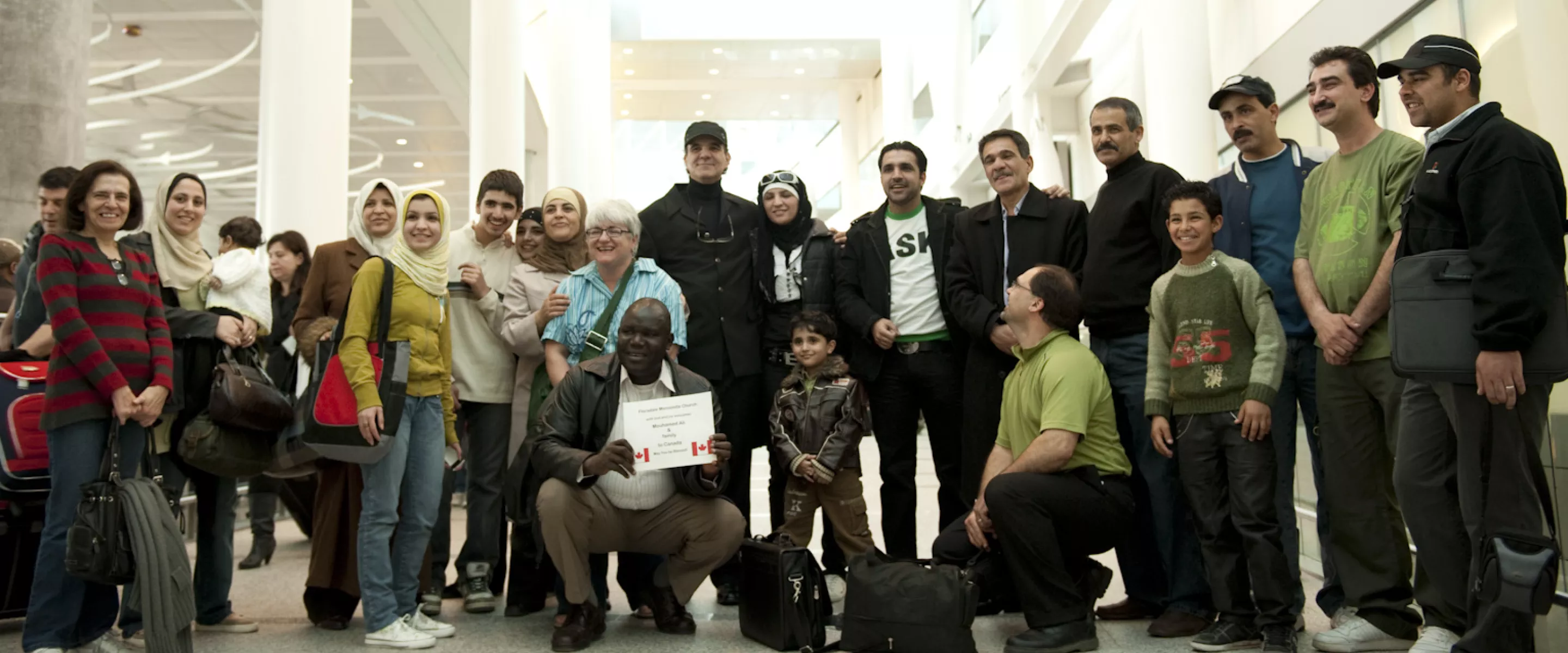 A large group of people pose together at an airport