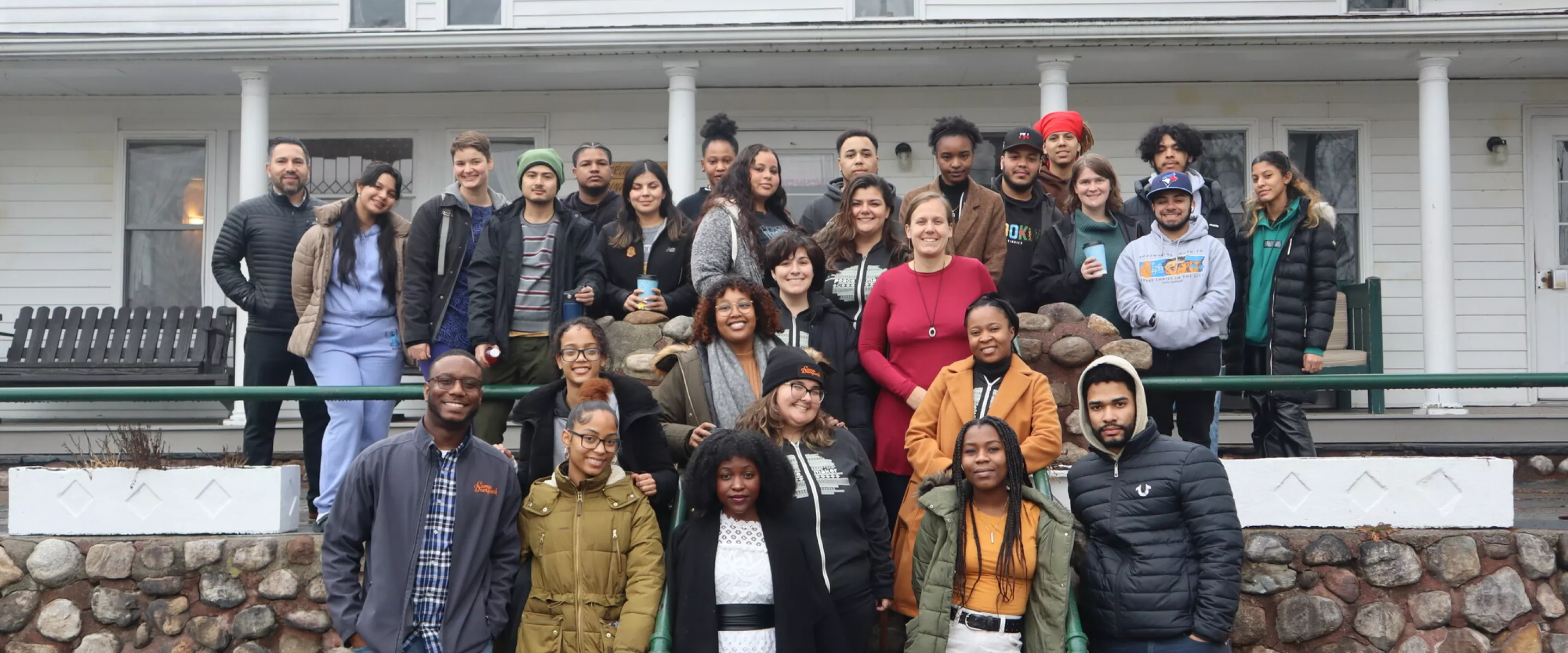 Young adults posing for group photo on steps outside of a building.