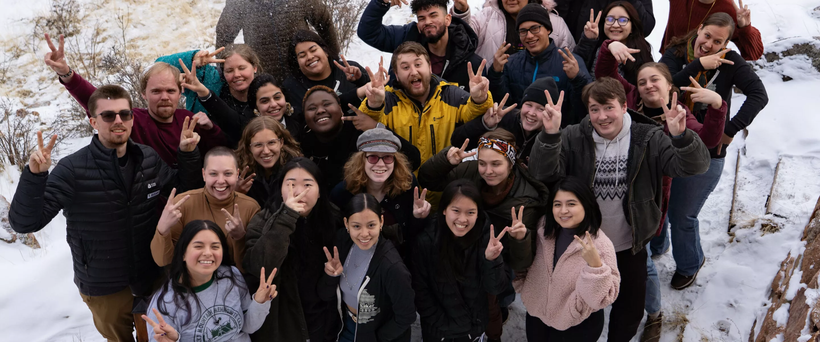 Young adults stand in a group pose in the snow.