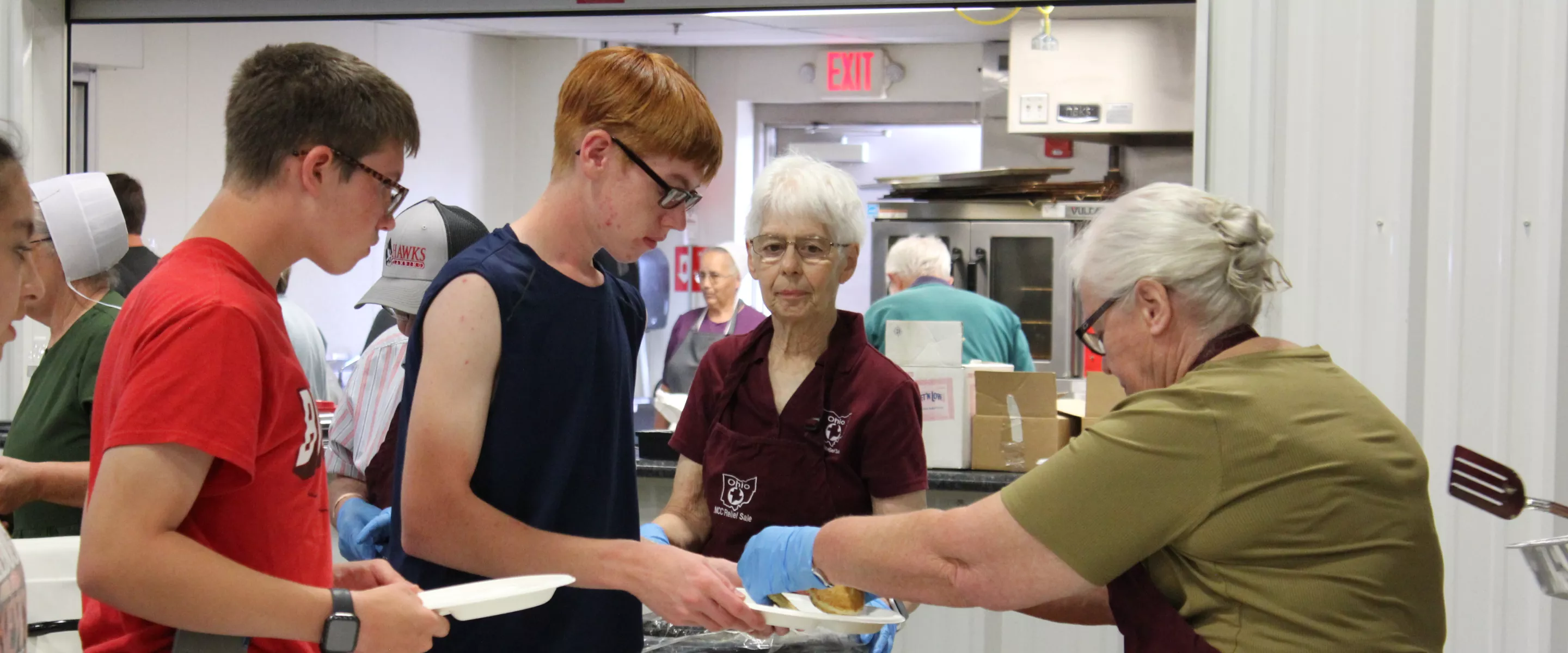 woman serving pancakes to two boys