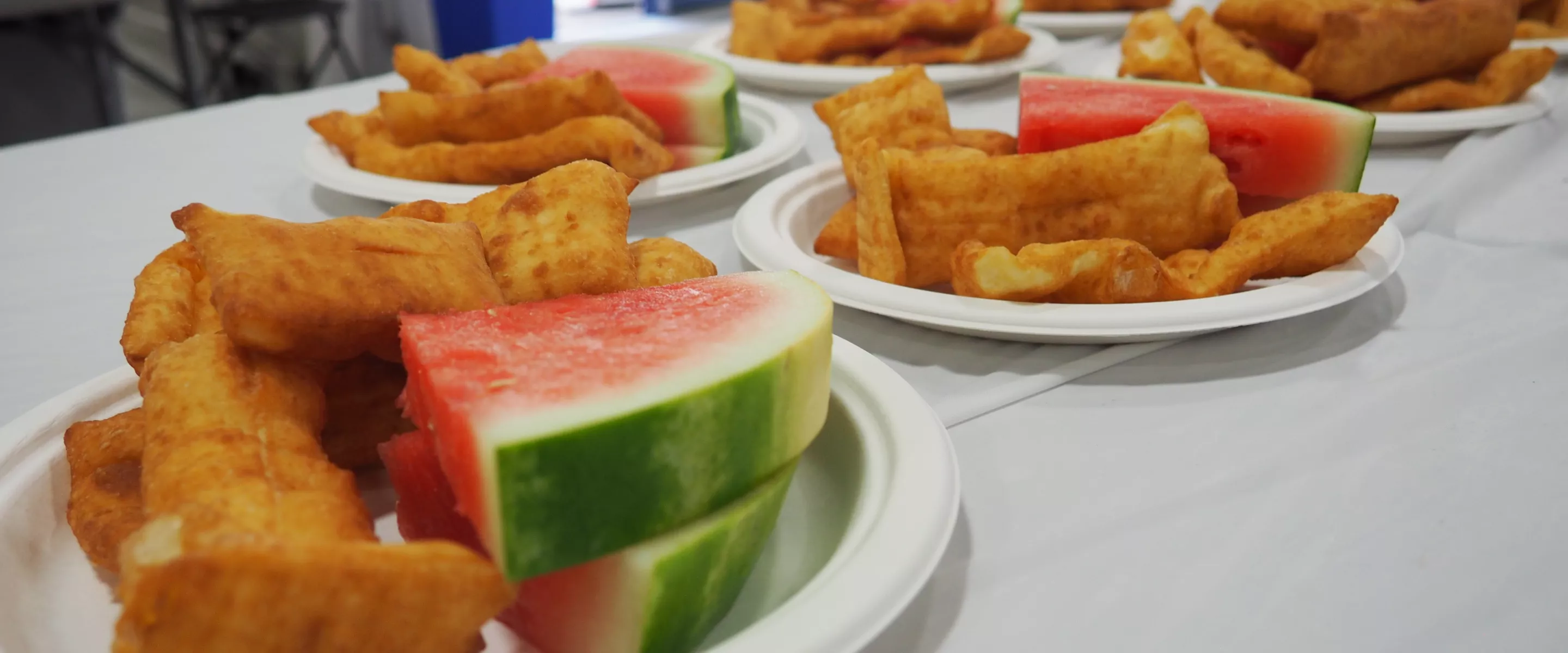 Multiple plates of watermelon and rollkuchen sitting on a table.