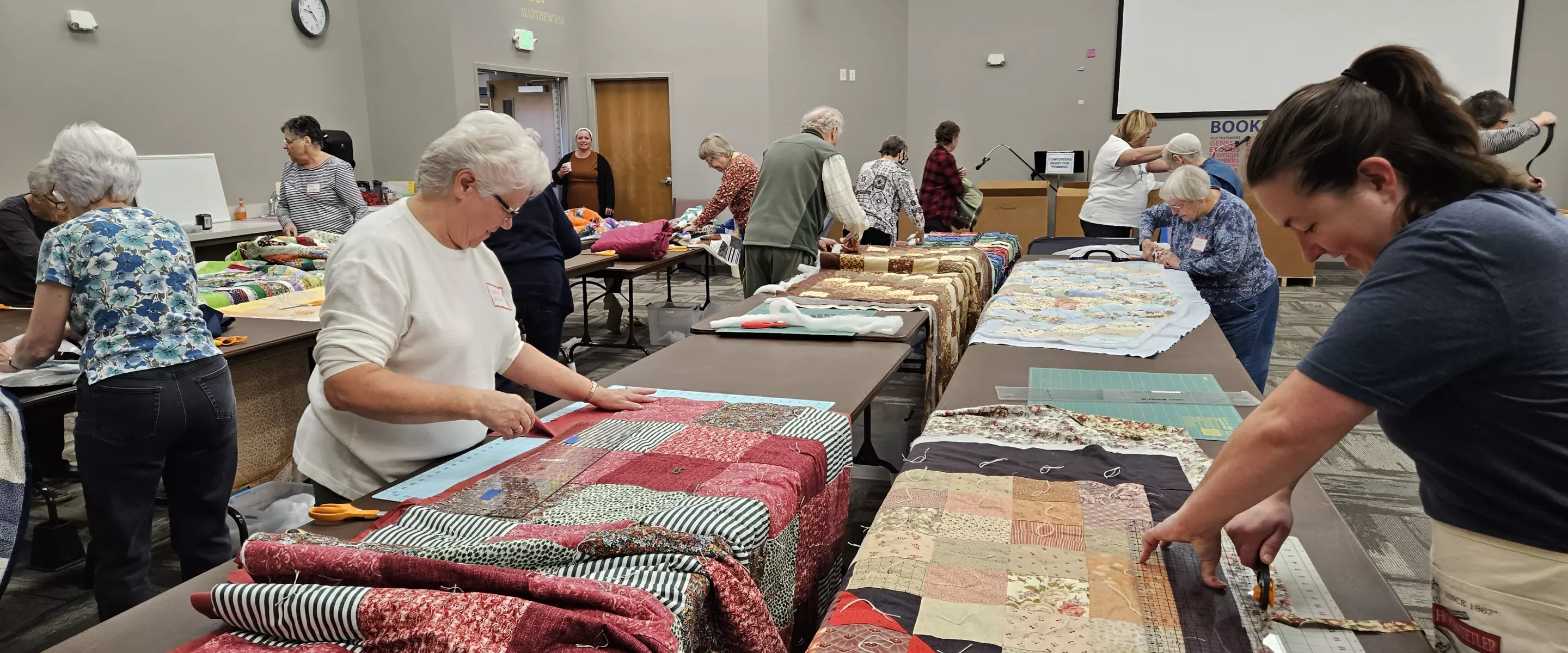 two women trim the edges of comforters 