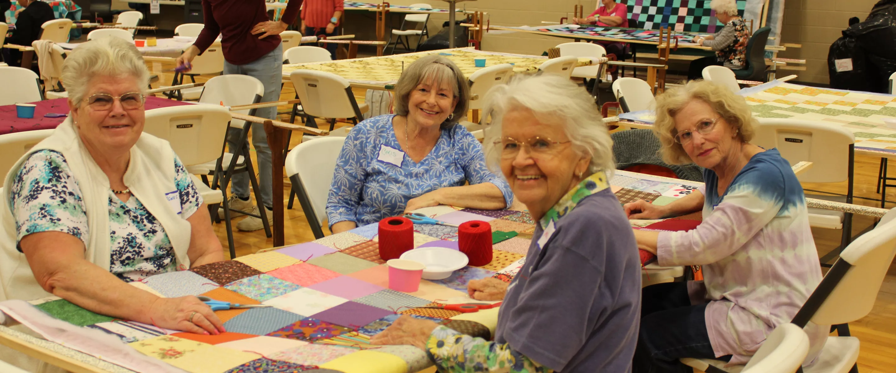 group of women sit around comforter and smile at camera