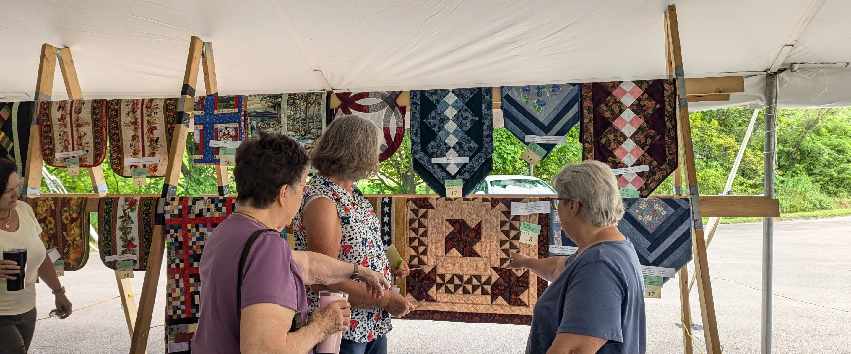 Women admiring quilts on a rack