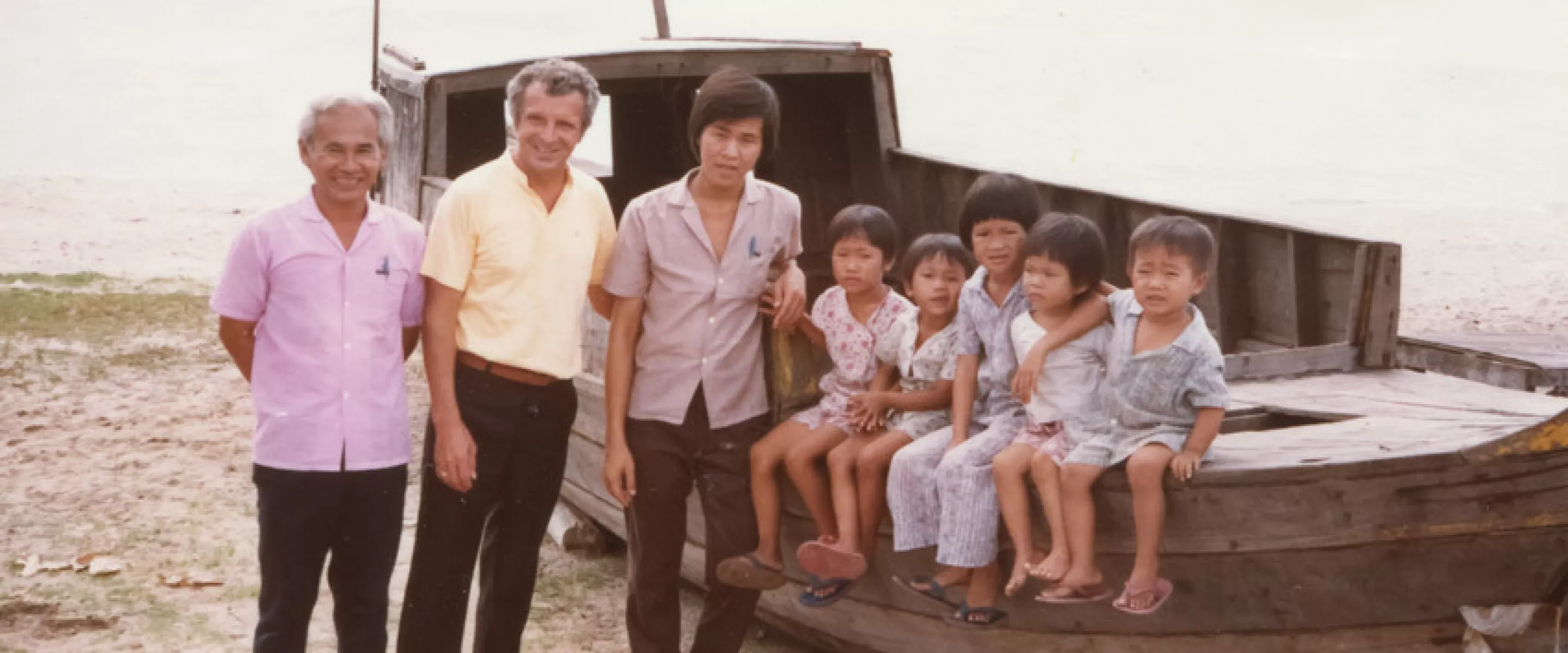 Victor Neumann, MCC representative in Songkhla, Thailand, with Vietnamese Boat People. Mothers of children shown here were abducted by pirates.In response to the refugee crisis following the end of