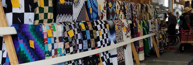 A large number of quilts on display before an auction