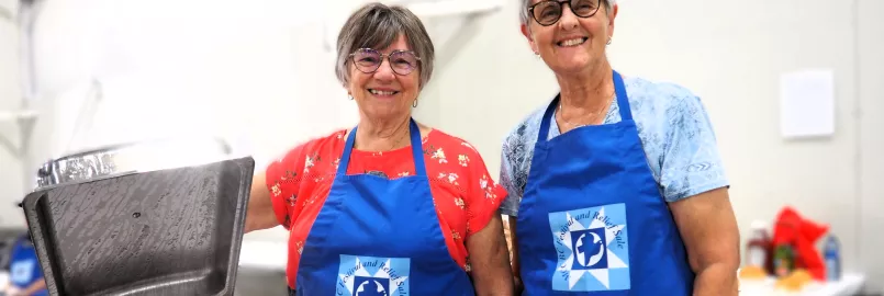 Two Festival volunteers at the MCC Festival for World Relief. With a chafing dish of Mennonite sausage