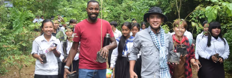 MCC Cambodia staff and students from a local school carry saplings to plant in a deforested area in the Monks Community Forest in northwest Cambodia.