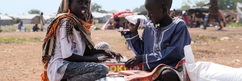 Zero Mawang Juch  (left) and Sudan Koang Ruei at the distribution site with a portion of food supplies. Each bag of sorghum is about 15kgs, so it is heavy for program participants to carry on their he