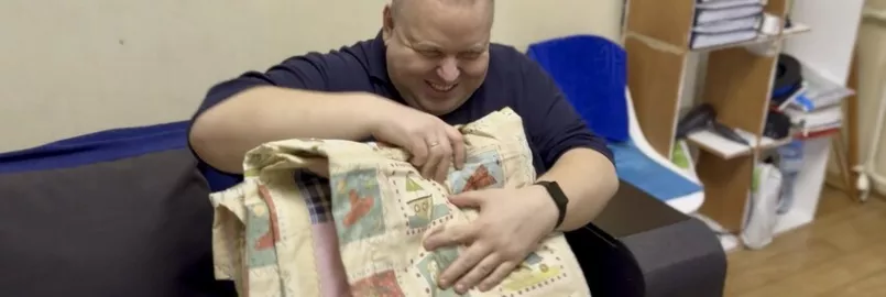 Serhiy,* who is blind,  examines the new MCC comforter he just received from MCC partner New Life in Nikopol, Ukraine.*Family name is withheld for security reasons.