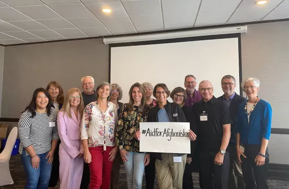 Board members of MCC Canada holding a sign reading #aidforafghanistan