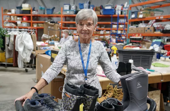 A woman standing in a thrift store stock room