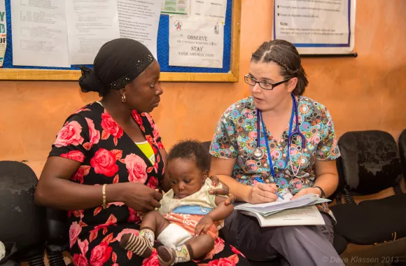 A woman talking to a mother holding her child