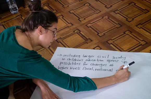 A young woman writing on a large piece of paper