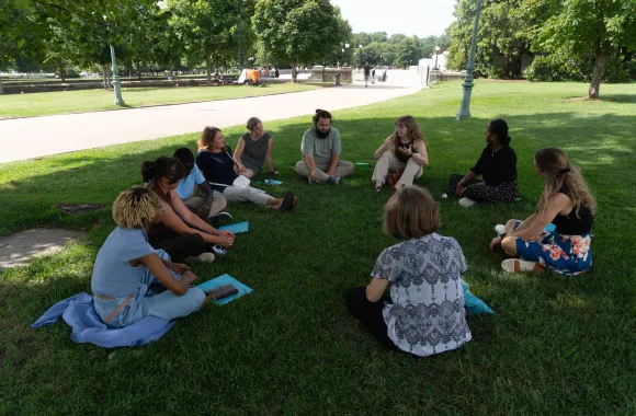 Students sit in a circle in the grass