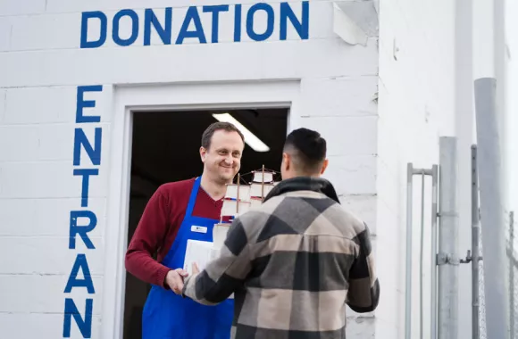 Thrift shop volunteer Alexander Germann accepts a box of donations from Jorge Morales at the donation entrance of the Edmonton MCC Thrift Shop.