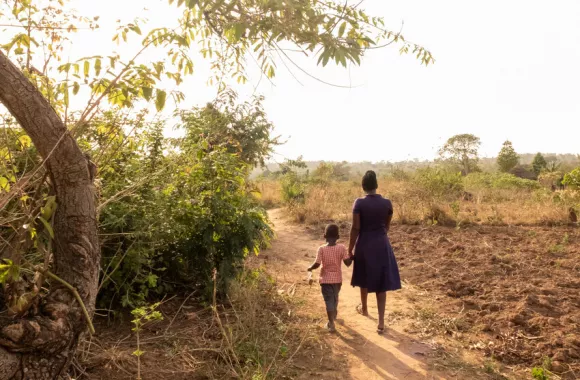 Mary Ilero, 30,  walks through a field with her son Ephraim Ekadu at the family’s farm outside of Soroti City, Uganda.