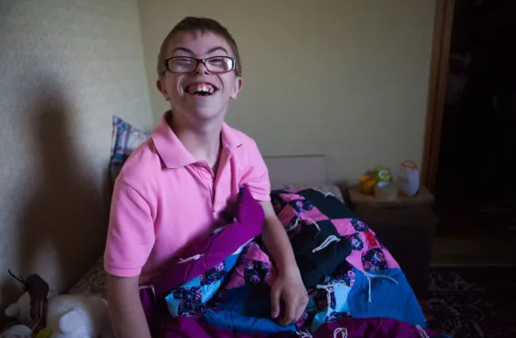 A young boy shows his MCC comforter from his home in Ukraine. His family received comforters, food and other emergency supplies through an MCC partner in Ukraine. The name of MCC’s partner in this wor