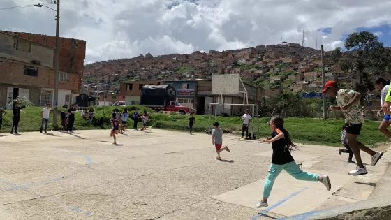 Children running onto a makeshift pitch in a school yard in Colombia.