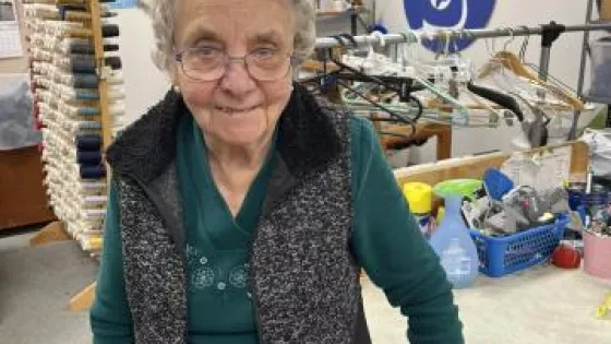 A woman smiling in an MCC thrift shop