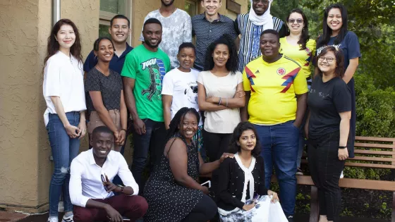 A group of 16 young adults of different nationalities pose for a photo