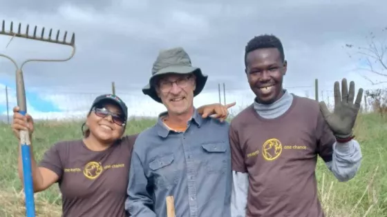 Three people standing for a photo on a farm