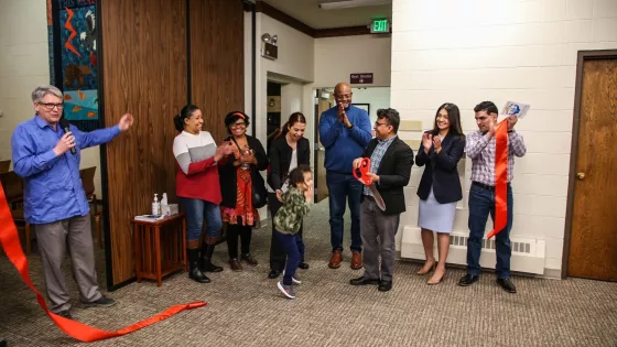 a group of men, women and one child standing and clapping