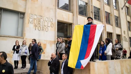  man holds a Colombian flag with an added white stripe to represent peace.