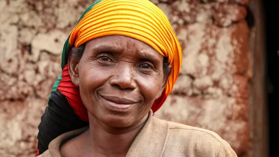 A portrait of a Burundi woman with a colorful scarf around her head