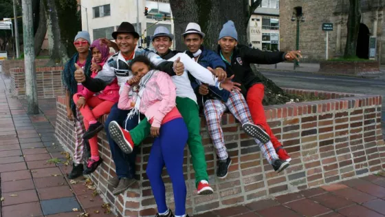 A group in colourful pants sit on a brick wall.