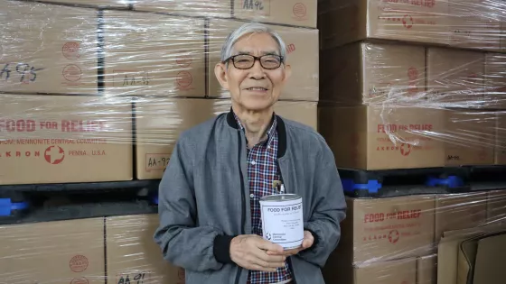 David Suh holds canned meat at the Material Resources Center. 