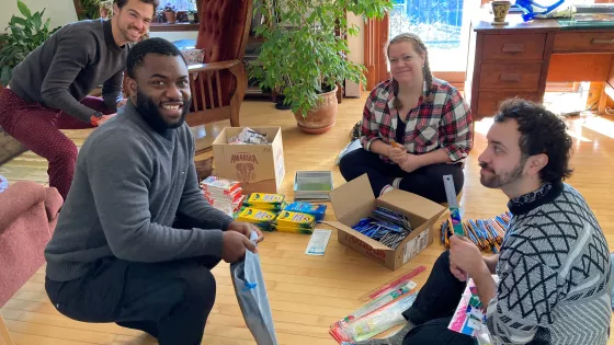 A group of four people smiling for a photo as they pack relief kits