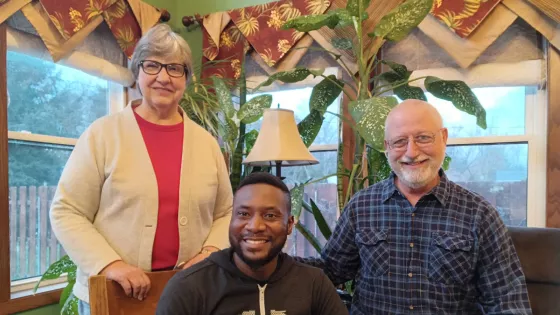 A young man smiles for a photo with an older couple