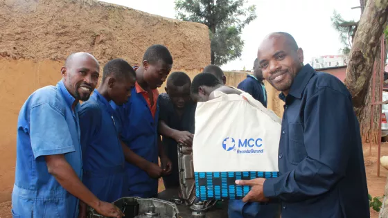 a group of participants in a vocational training session surround an engine