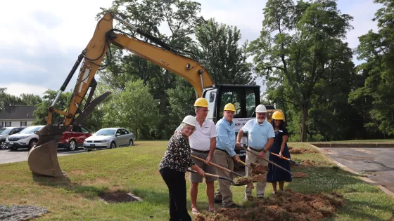 MCC staff and a volunteer lift dirt in their shovels on the site where the Material Resources Center (MRC) will be expanded.  From left to right: Carol Zook, Material Resources Center manager for MCC