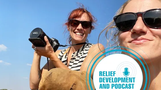 two women smiling, one is holding a camera